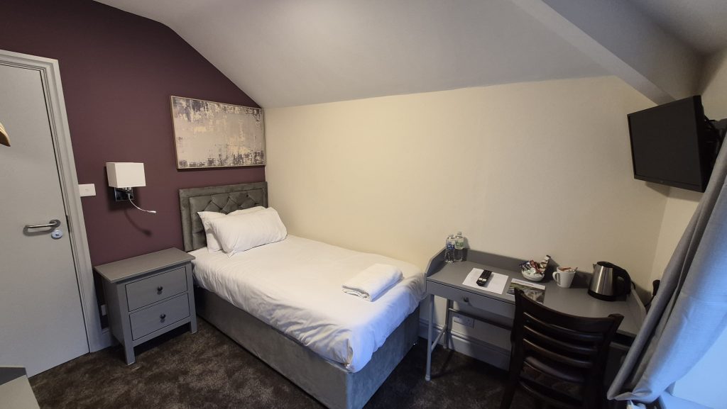 Single room at The Lemon Tree hotel in Wrexham with a single bed, desk and wall-mounted TV