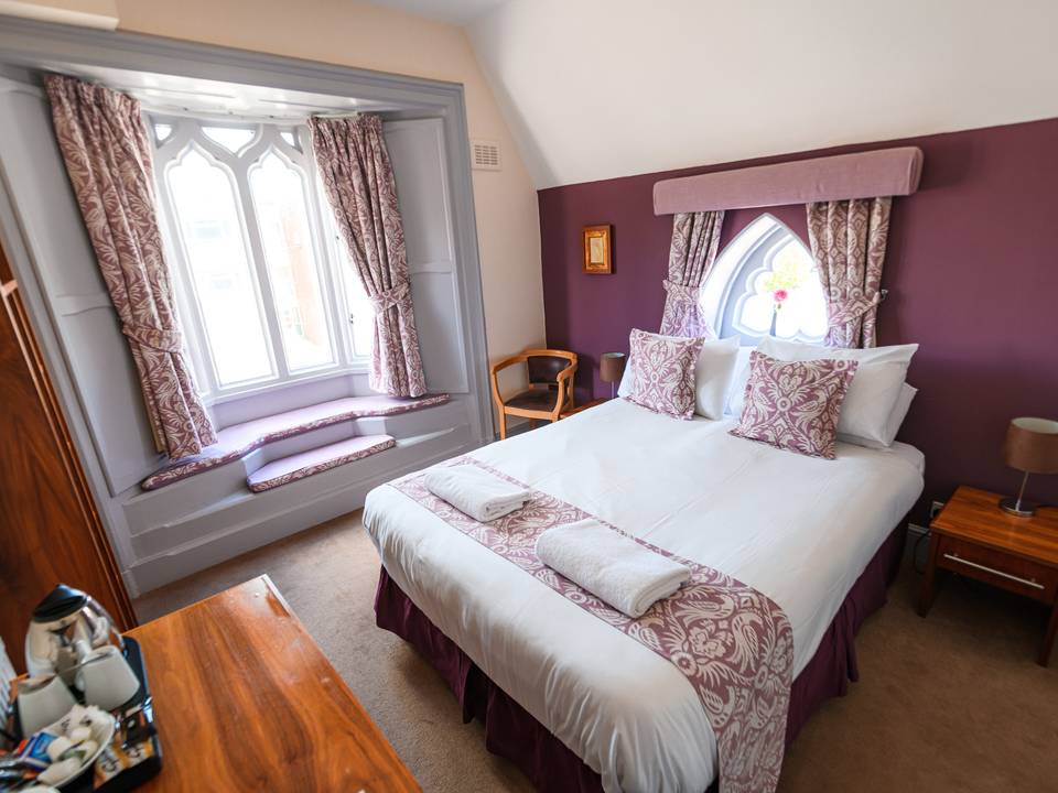 Double room at The Lemon Tree hotel in Wrexham with a bay window seat and an arched gothic window above the bed