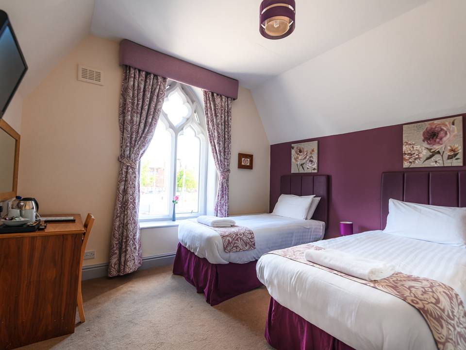 Twin room at The Lemon Tree hotel in Wrexham with two single beds beneath an arched gothic window
